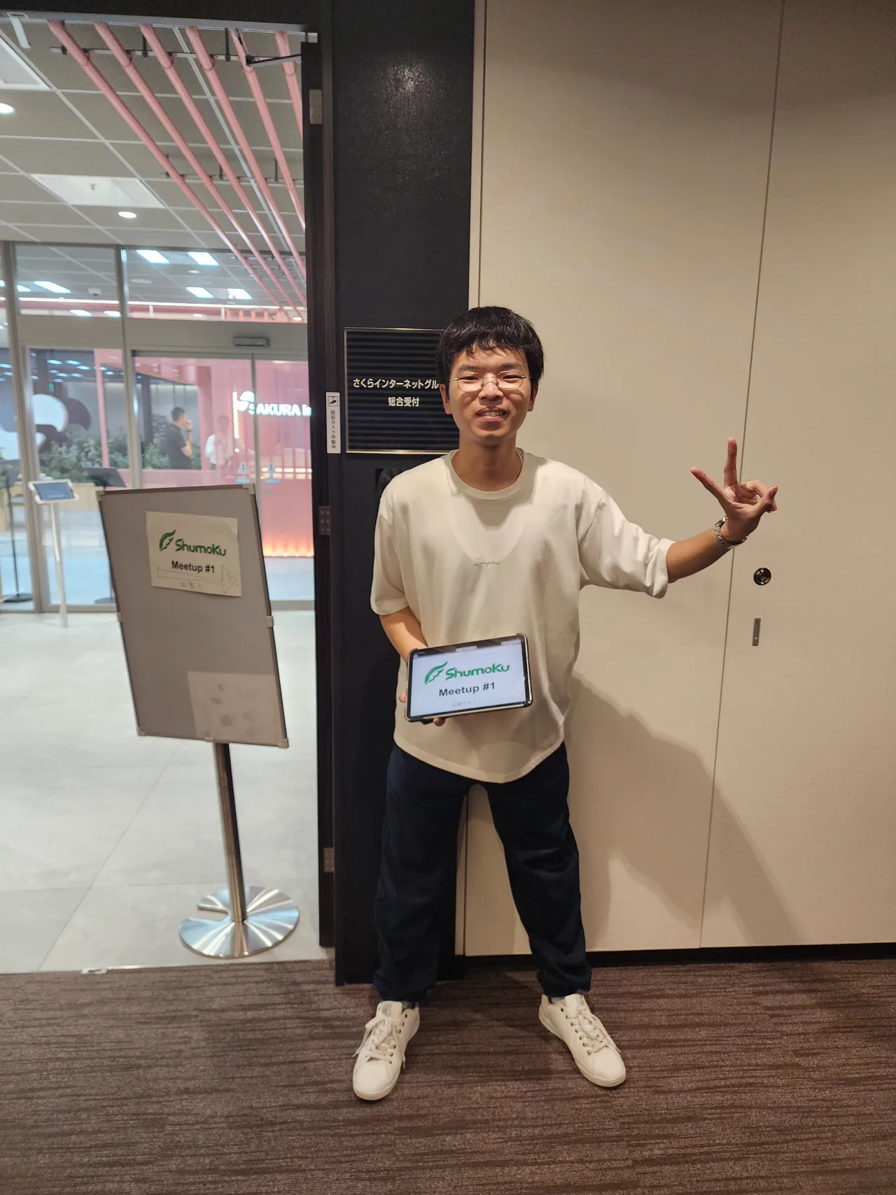 Shumokuの案内を持って入口で参加者を迎えるスタッフ。